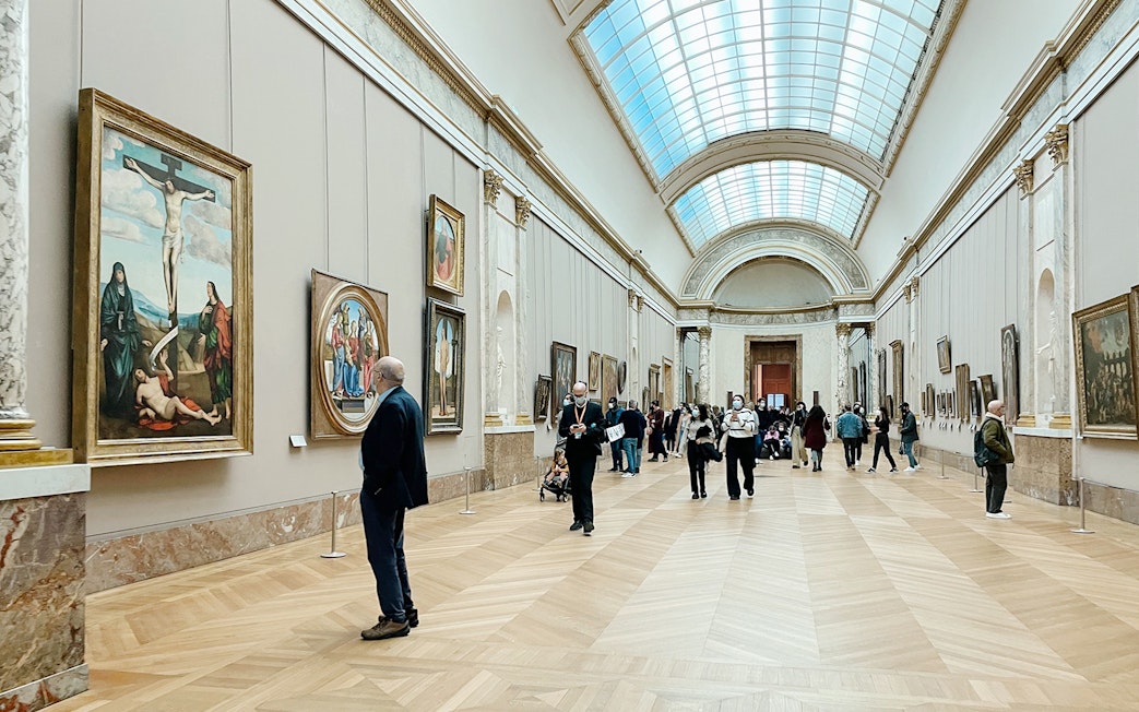 Visitors viewing paintings in a gallery at the Louvre Museum, Paris, France.