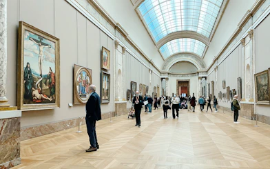 Visitors viewing paintings in a gallery at the Louvre Museum, Paris, France.