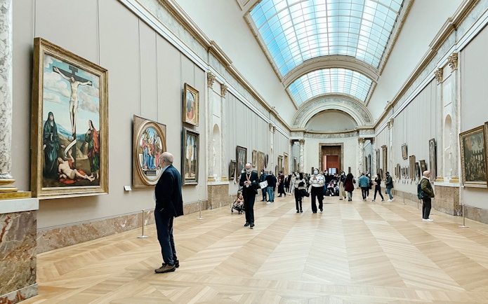 Visitors viewing paintings in a gallery at the Louvre Museum, Paris, France.