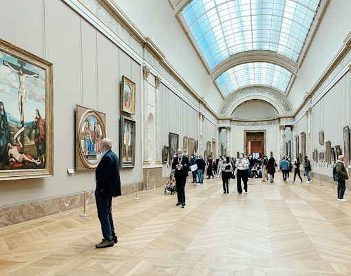 Visitors admiring the intricate drawings and paintings at the Louvre Museum in Paris, a popular tour destination