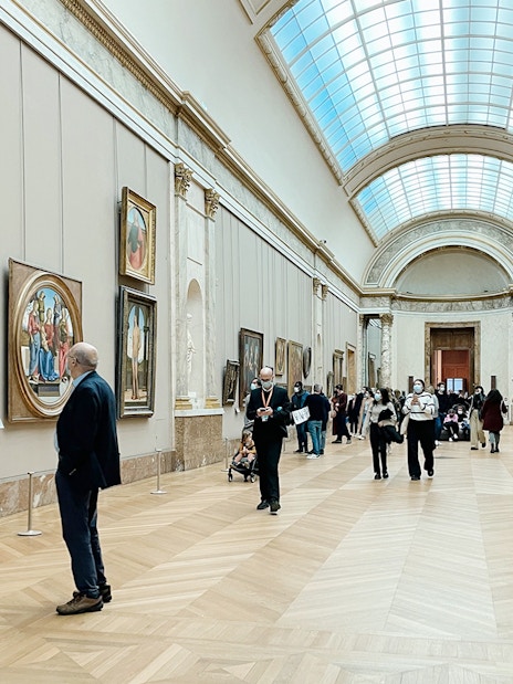 Visitors viewing paintings in a gallery at the Louvre Museum, Paris, France.