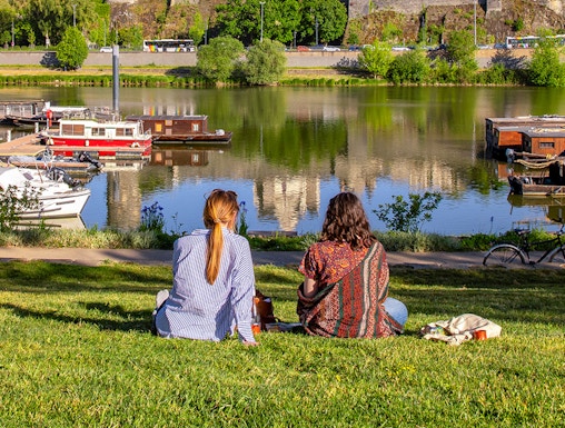 Two people sitting by the river with a view of Château d'Angers, Loire Valley.