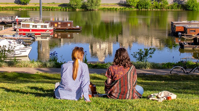 Two people sitting by the river with a view of Château d'Angers, Loire Valley.