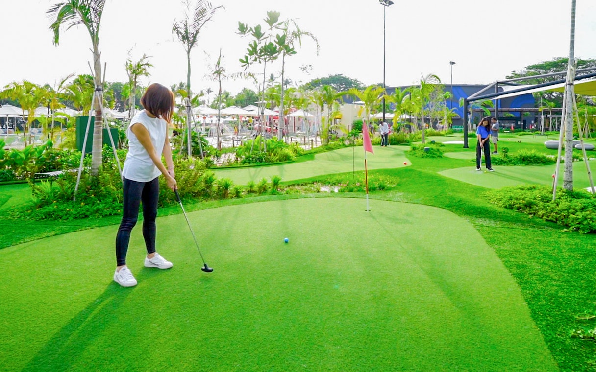 People playing mini-golf on a lush green course, part of the Combo: HyperDrive and UltraGolf experience.