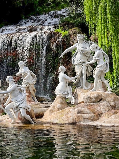 Statues near waterfall at Royal Palace of Caserta gardens.