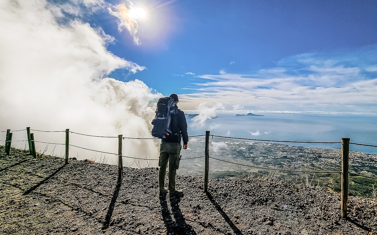 Hiker overlooking the view from Mount Vesuvius summit, Italy.