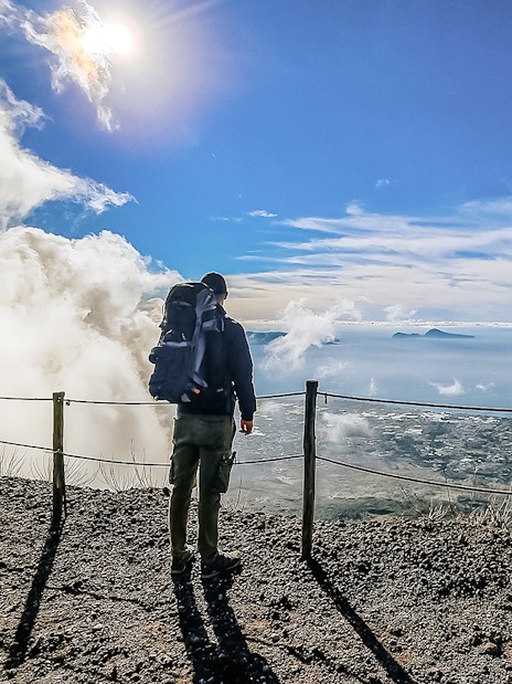 Hiker overlooking the view from Mount Vesuvius summit, Italy.