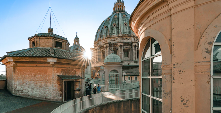 People walking down the dome of St Peter's Basilica, Vatican City, with sunlight peeking through.