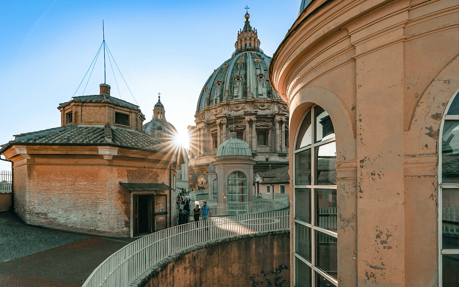 People walking down the dome of St Peter's Basilica, Vatican City, with sunlight peeking through.