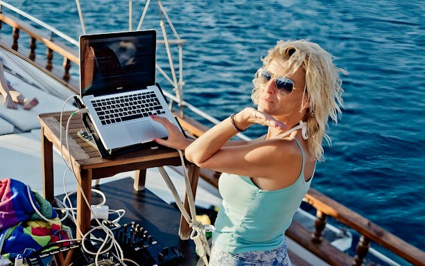 DJ performing on Athens Riviera cruise with city lights in the background.