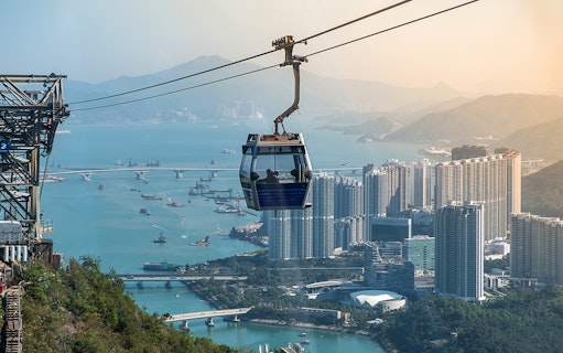 Ngong Ping Cable Car over Hong Kong skyline and harbor.