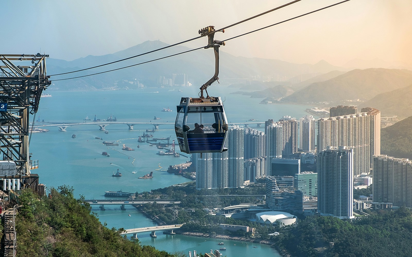 Ngong Ping Cable Car over Hong Kong skyline and harbor.