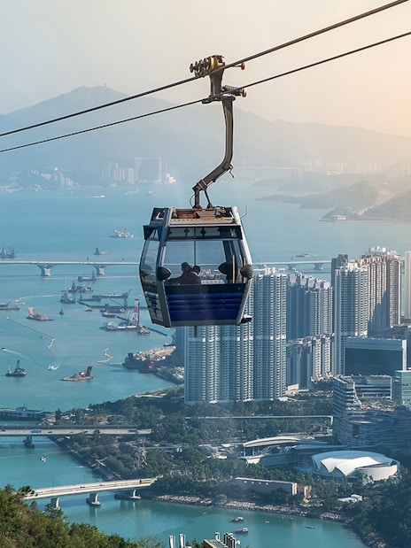 Ngong Ping Cable Car over Hong Kong skyline and harbor.