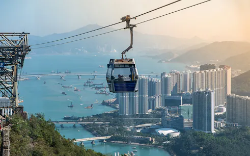 Ngong Ping Cable Car over Hong Kong skyline and harbor.