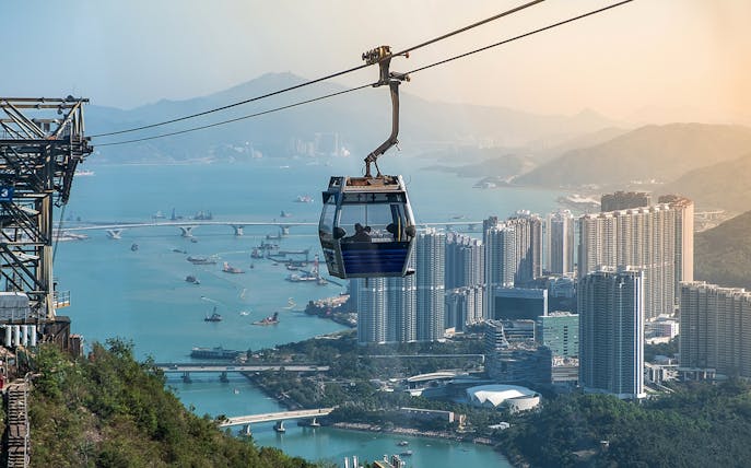 Ngong Ping Cable Car over Hong Kong skyline and harbor.
