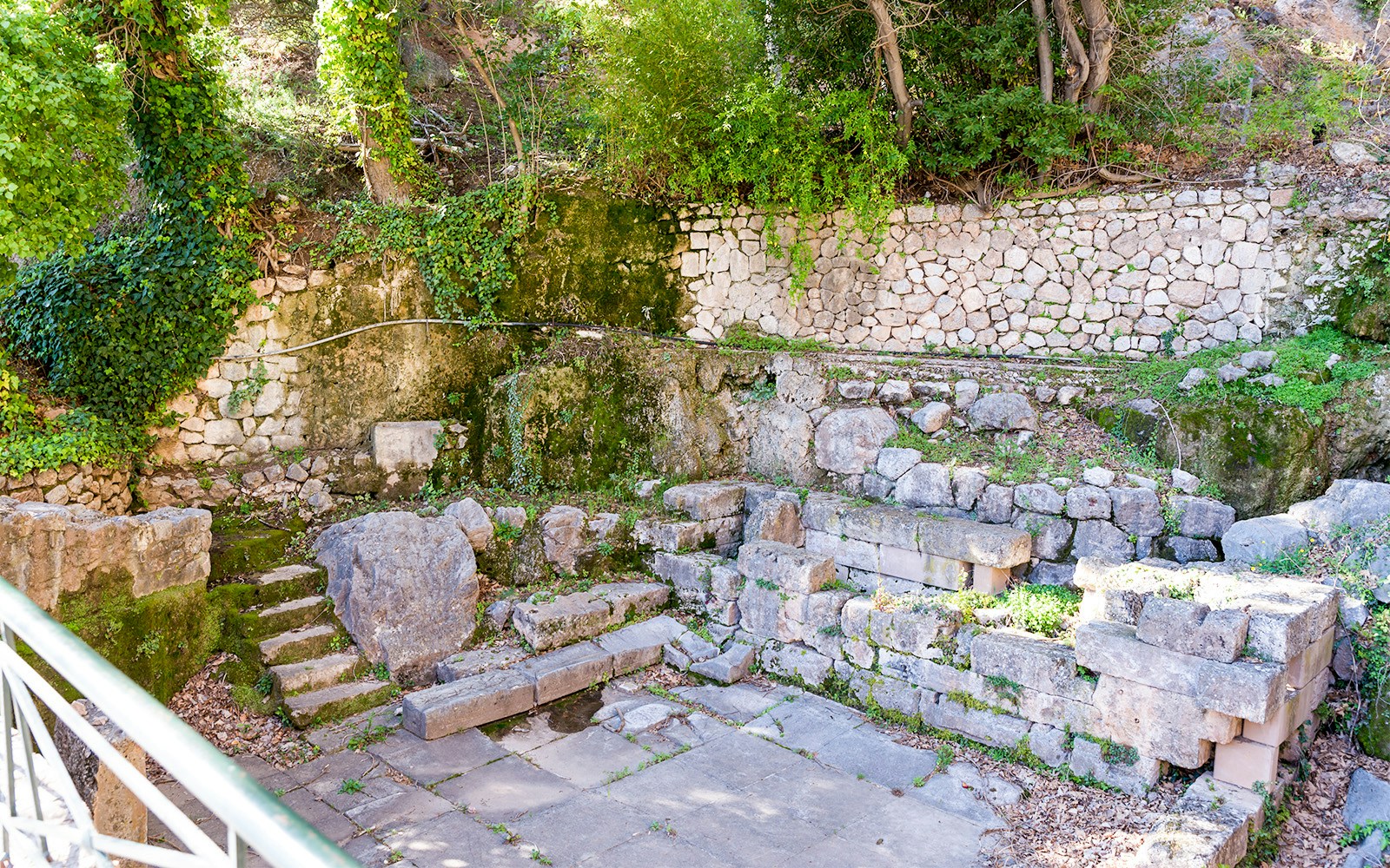 Delphi Castalian Spring stone ruins with surrounding greenery.