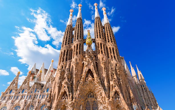 Sagrada Familia's intricate facade under a clear blue sky in Barcelona.