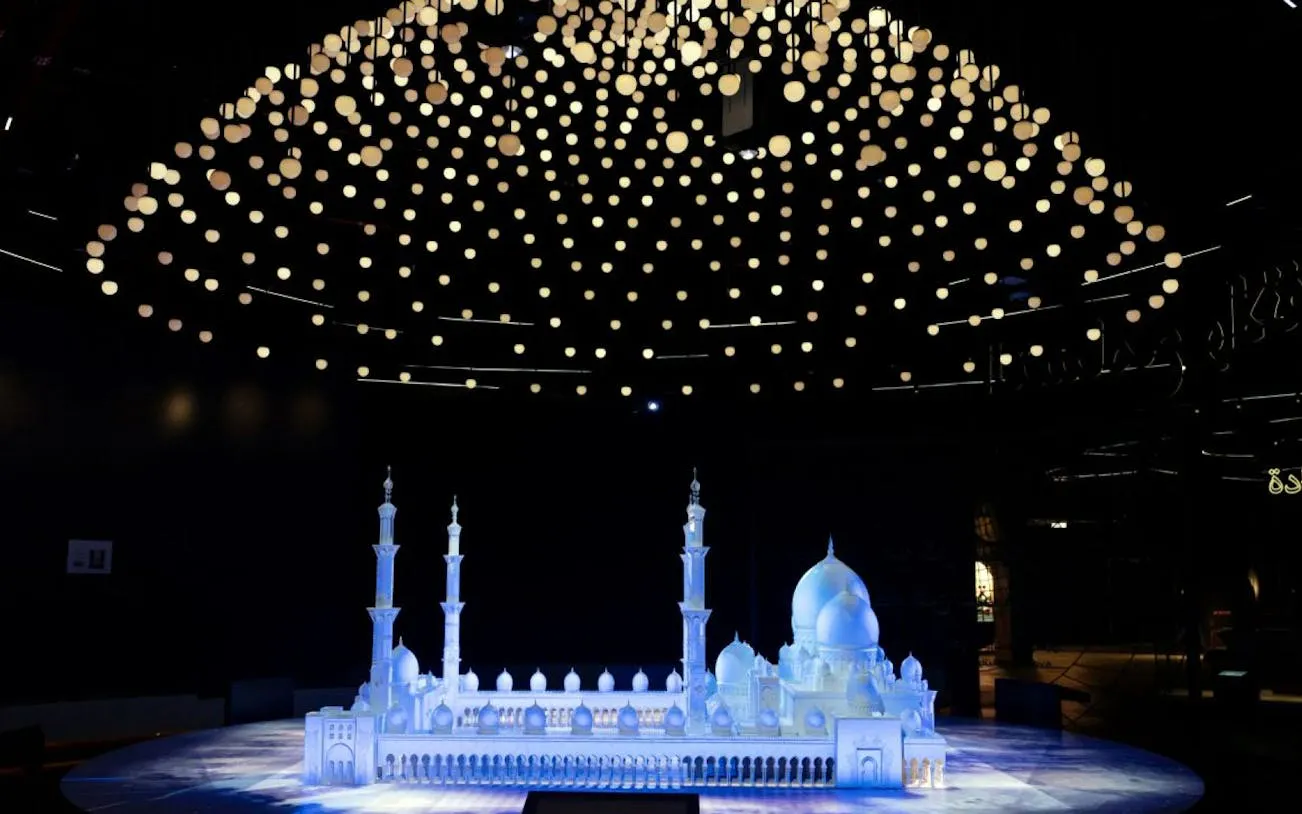 Model of Sheikh Zayed Grand Mosque under illuminated ceiling at Light & Peace Museum.