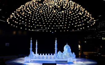 Model of Sheikh Zayed Grand Mosque under illuminated ceiling at Light & Peace Museum.