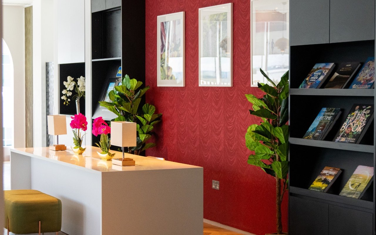 Plaza Premium Lounge seating area with plants and bookshelves, London Gatwick Airport.