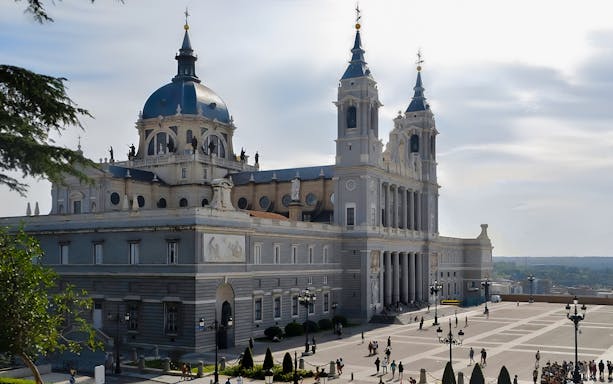 Royal Palace of Madrid exterior with tourists exploring the courtyard.