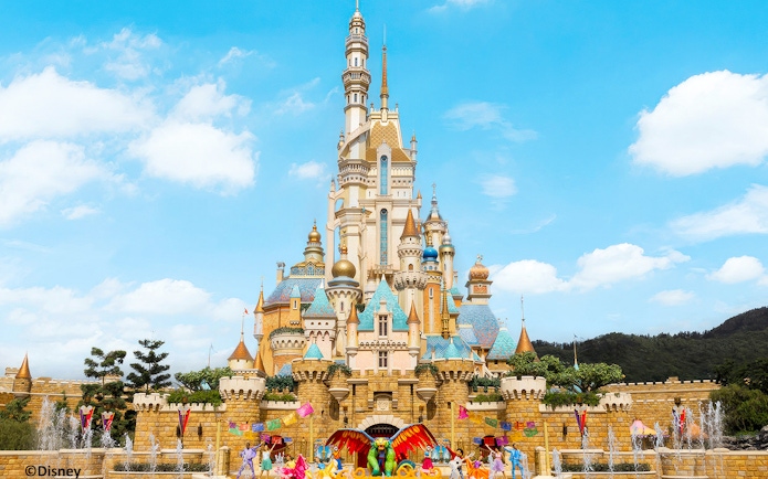 Hong Kong Disneyland castle with colorful decorations and performers in front.