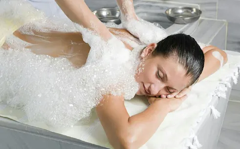 Person receiving a foamy massage in a traditional Moroccan hammam, Marrakech.