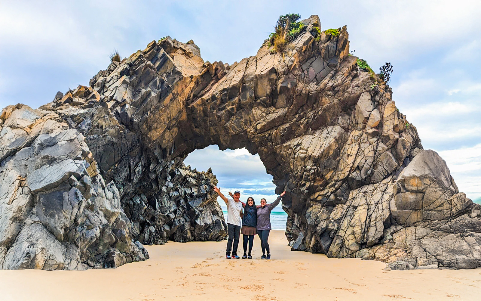 Tourists at Bruny Island exploring coastal rock arch on nature trail.