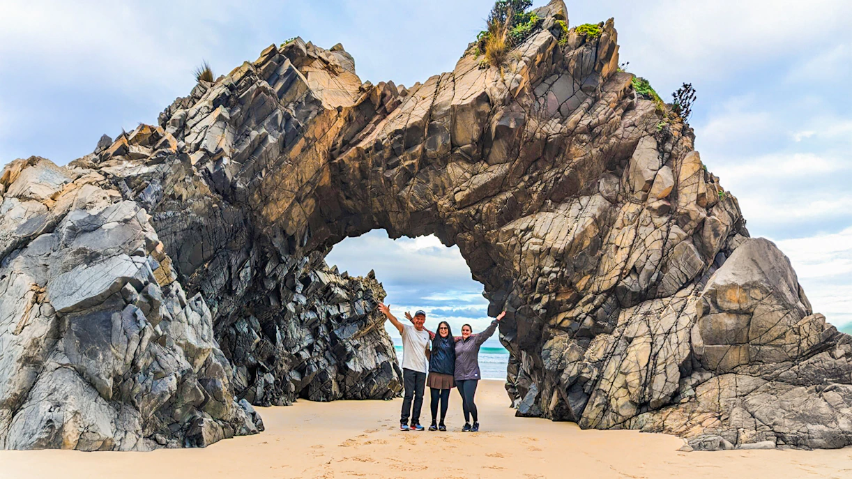 Tourists at Bruny Island exploring coastal rock arch on nature trail.