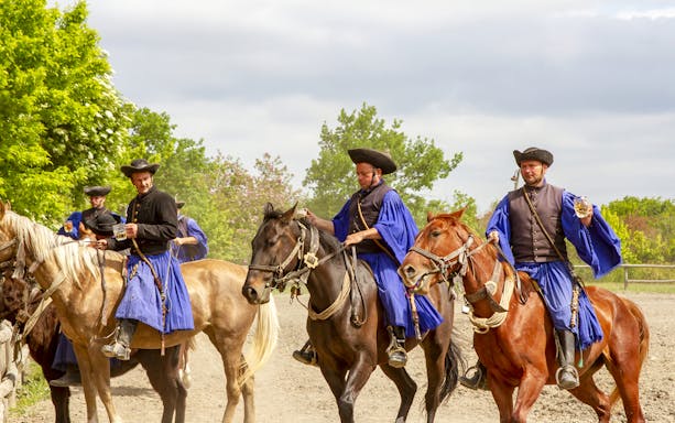 Horsemen in traditional attire performing at a Hungarian ranch near Budapest.
