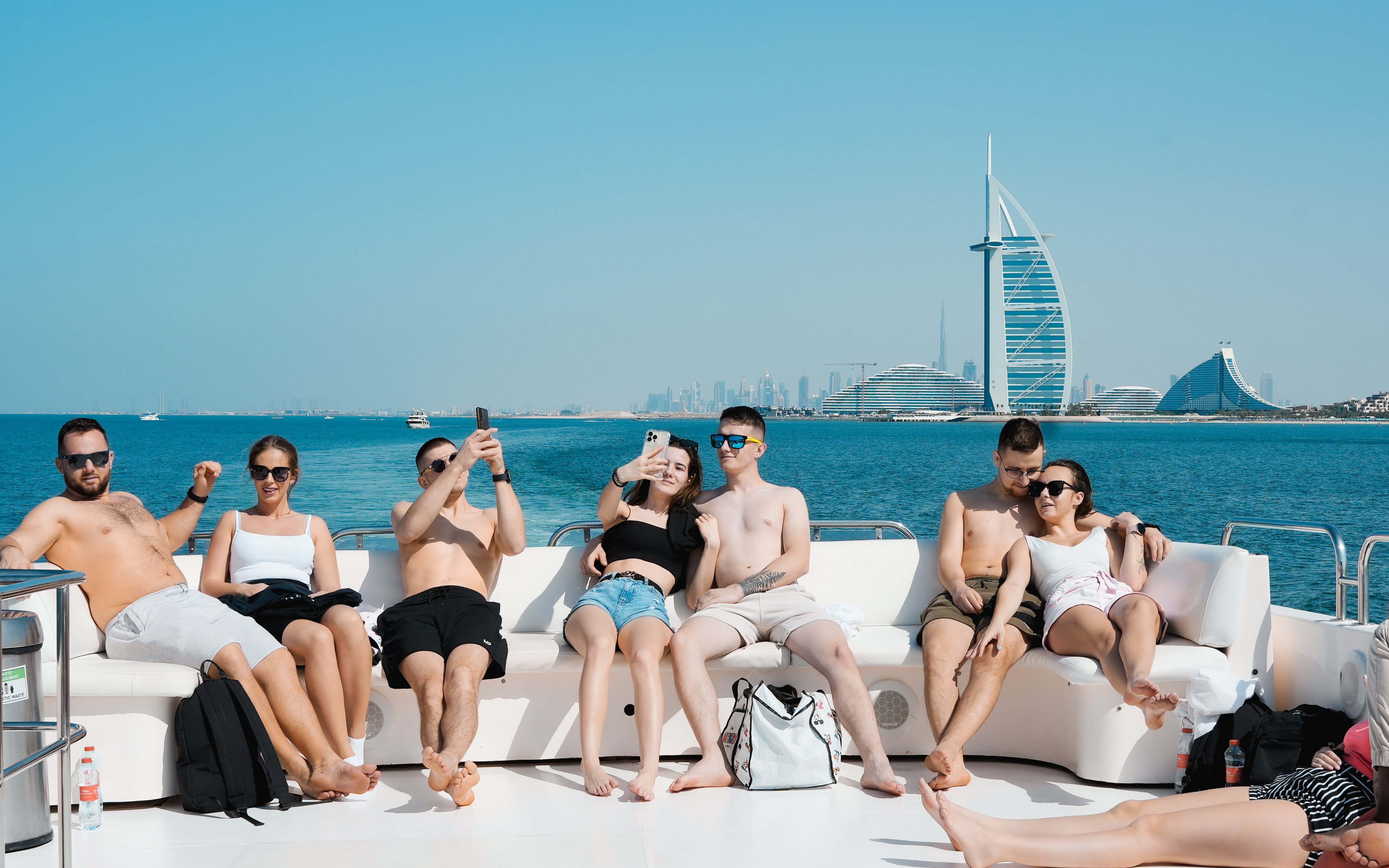 Group enjoying a yacht tour with Burj Al Arab in the background, Dubai Harbour.