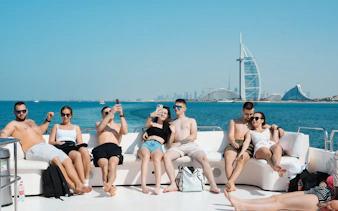 Group enjoying a yacht tour with Burj Al Arab in the background, Dubai Harbour.