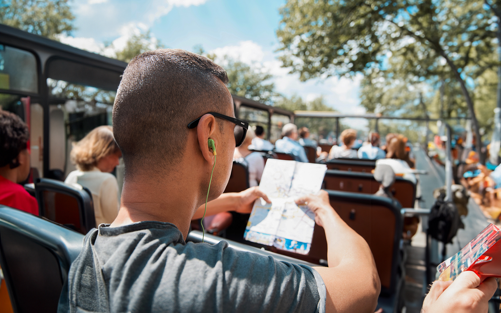 Tourists on a hop-on-hop-off bus in Vienna with audio guide and map.