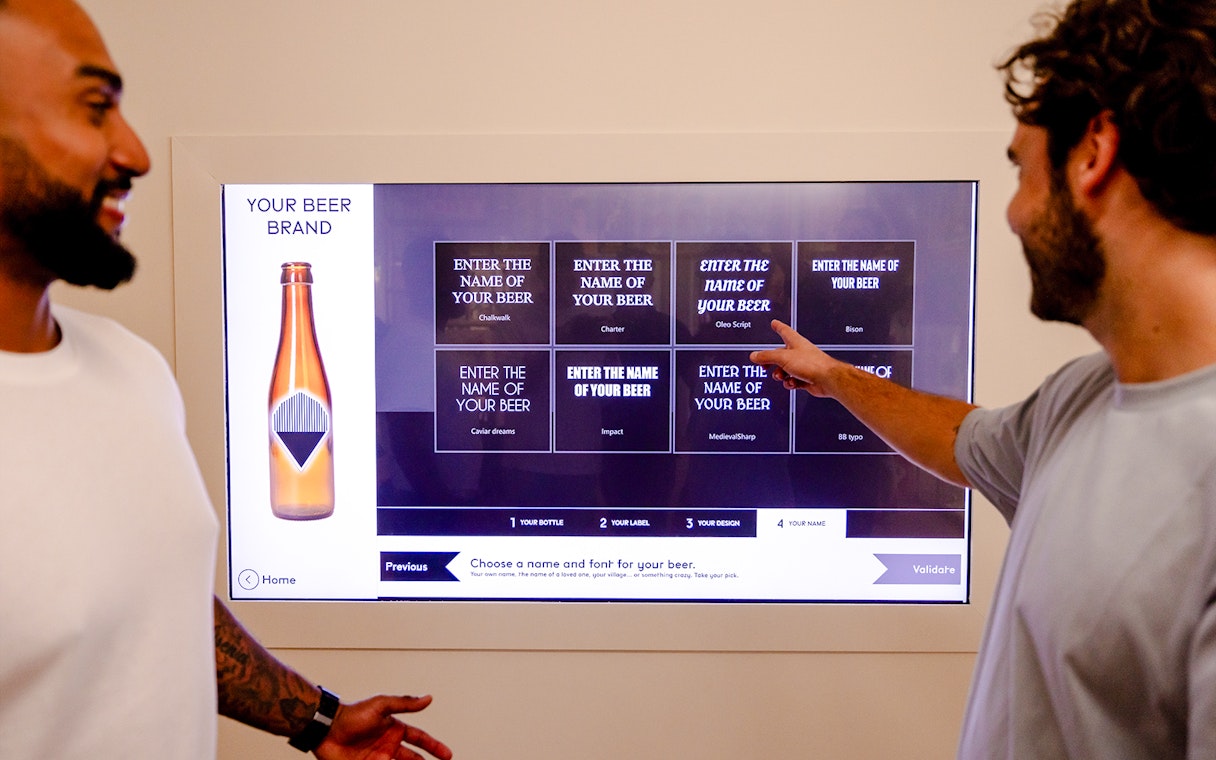 Guests interacting with a digital beer naming display at Belgian Beer World in Brussels.