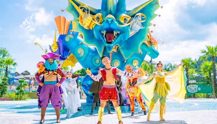 Performers in colorful costumes in front of a dragon sculpture at Andamanda Phuket.
