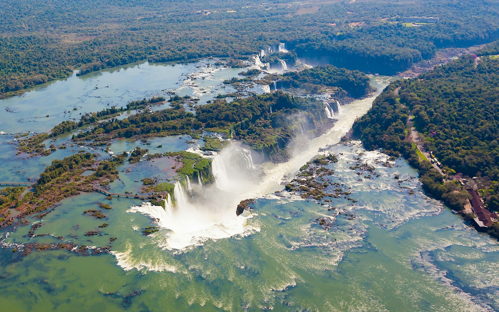 Aerial view of Iguazu Falls from a helicopter ride, showcasing cascading waterfalls and lush greenery.