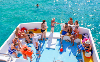 Tourists relaxing on a boat in the Blue Lagoon, Paphos, with clear turquoise water.