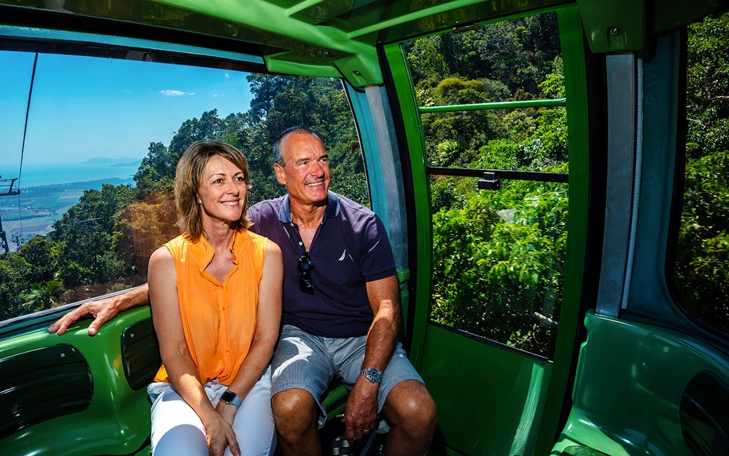 Couple enjoying Kuranda Skyrail Cableway with rainforest and coastline views in Cairns, Australia.