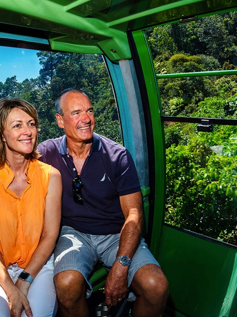 Couple enjoying Kuranda Skyrail Cableway with rainforest and coastline views in Cairns, Australia.