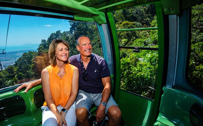 Couple enjoying Kuranda Skyrail Cableway with rainforest and coastline views in Cairns, Australia.