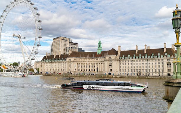 London Eye and County Hall viewed from a Thames Clippers boat on the River Thames.
