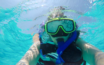 Snorkeler in clear waters of Mnemba Island Atoll, Zanzibar.