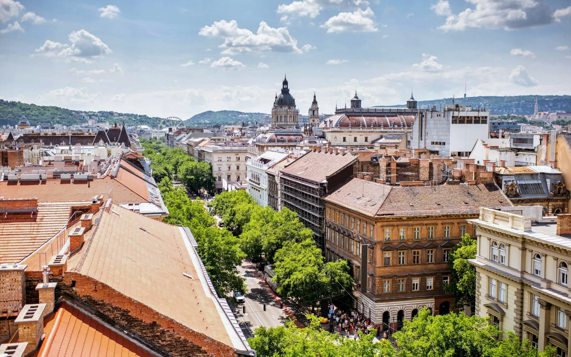 High-angle view of Andrássy Avenue in Budapest with St. Stephen's Basilica dome in the background.
