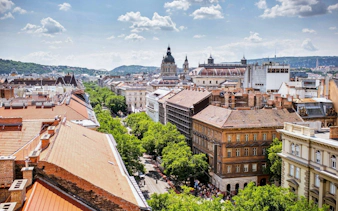 High-angle view of Andrássy Avenue in Budapest with St. Stephen's Basilica dome in the background.