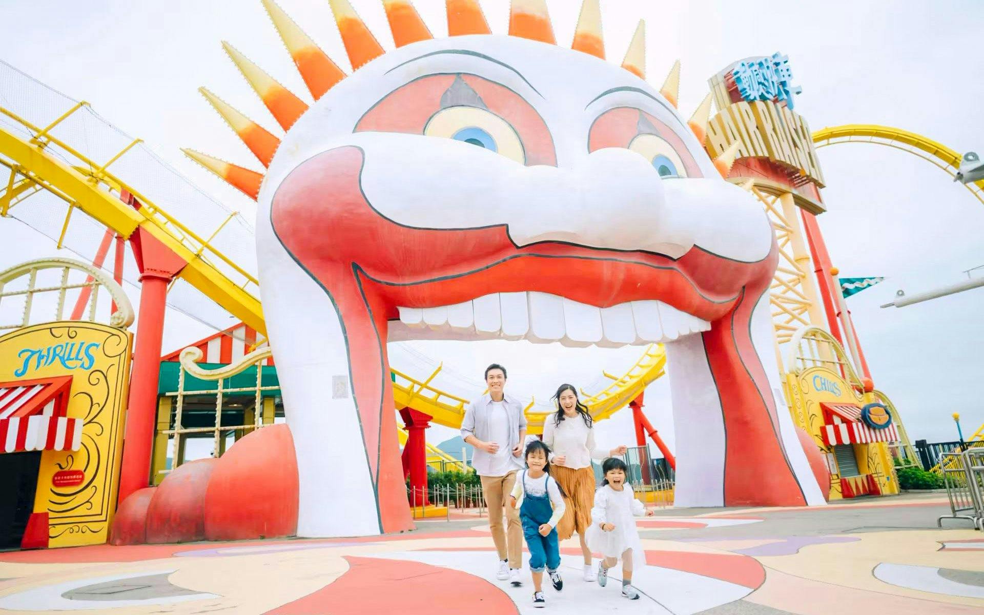 Family enjoying a day at Ocean Park with colorful roller coaster and clown entrance.