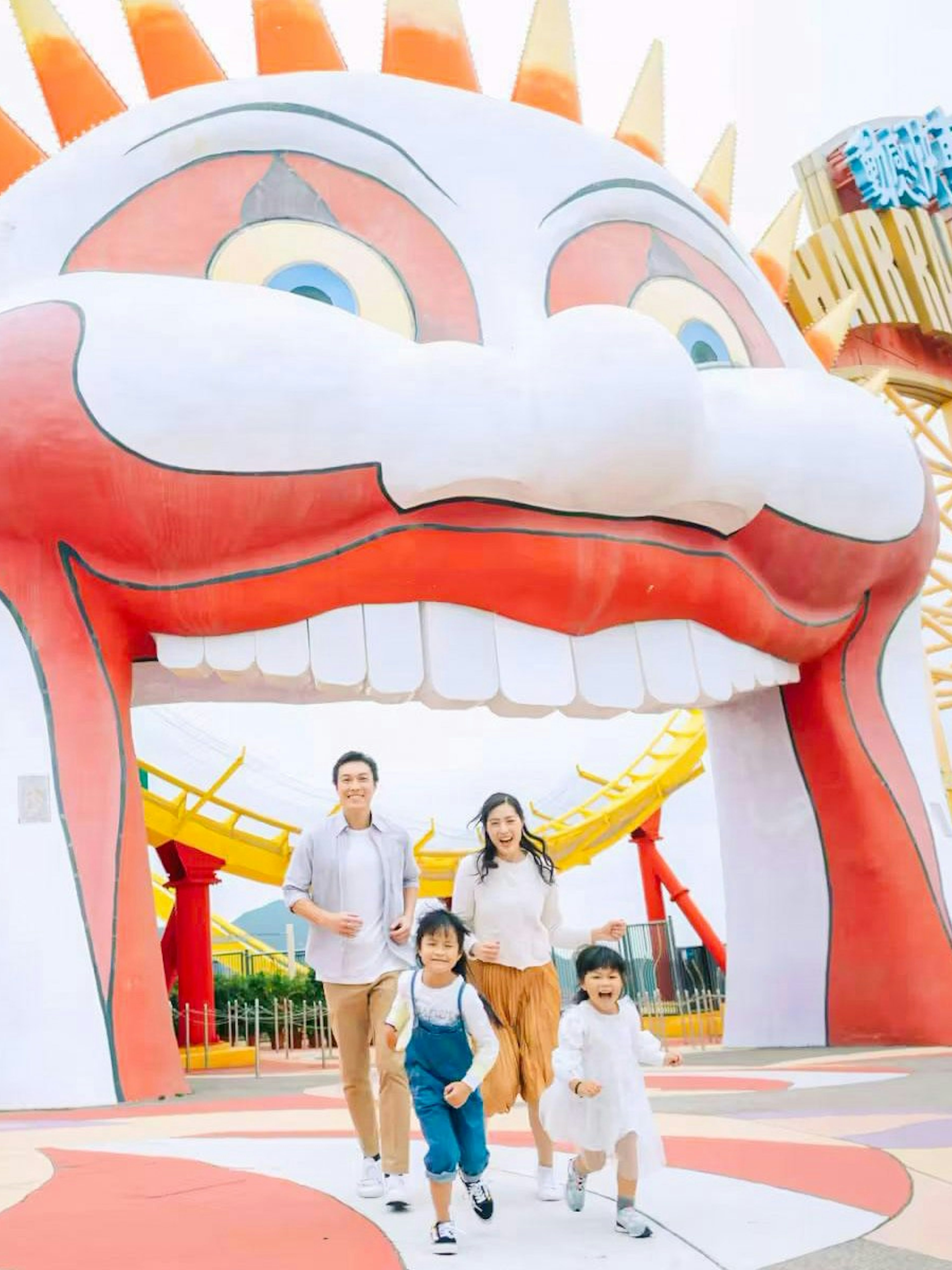Family enjoying a day at Ocean Park with colorful roller coaster and clown entrance.