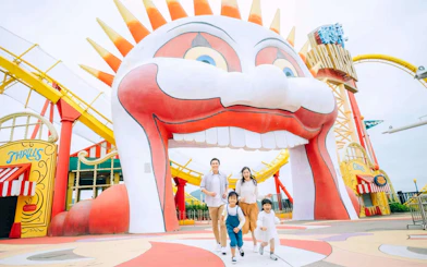 Family enjoying a day at Ocean Park with colorful roller coaster and clown entrance.