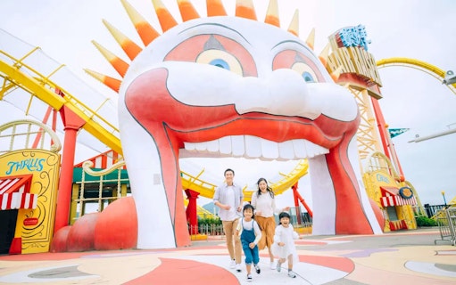 Family enjoying a day at Ocean Park with colorful roller coaster and clown entrance.