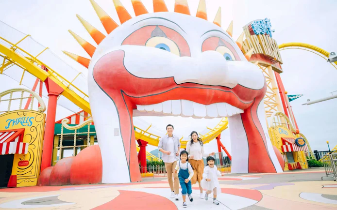 Family enjoying a day at Ocean Park with colorful roller coaster and clown entrance.