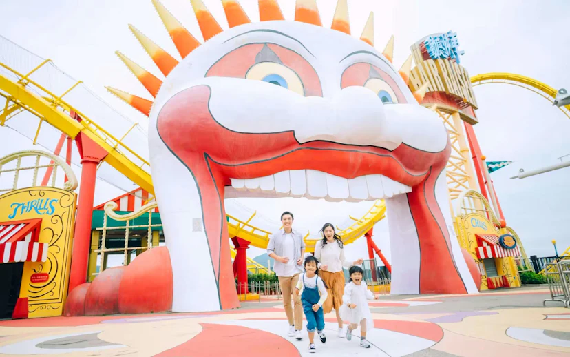 Family enjoying a day at Ocean Park with colorful roller coaster and clown entrance.